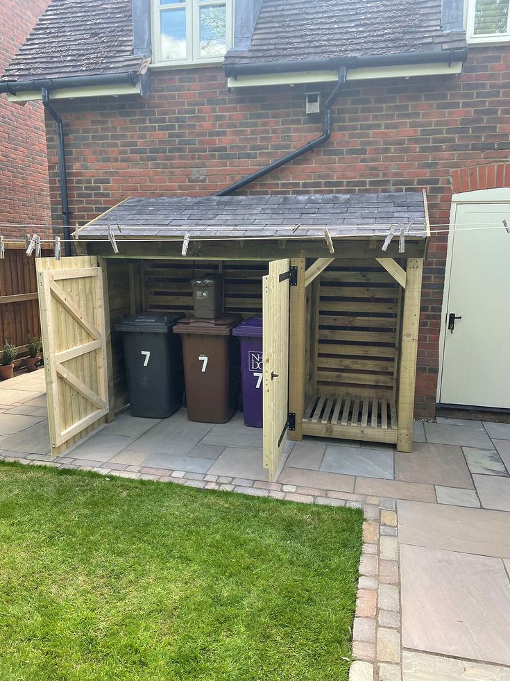 a wooden shed with two trash cans in it