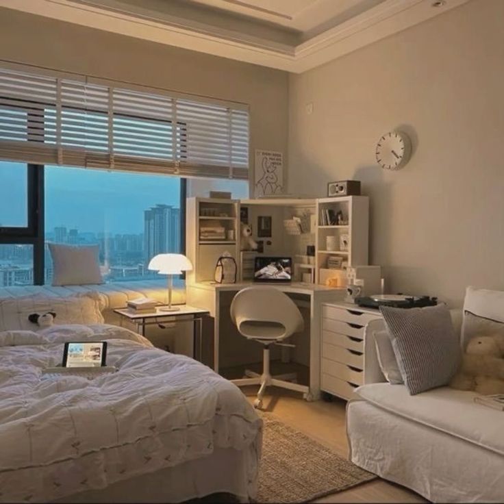 a bedroom with a bed, desk and chair next to a window overlooking the city