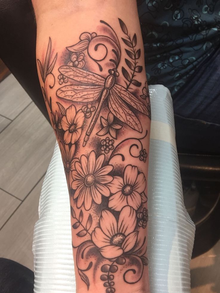 a woman's arm with flowers and a dragonfly tattoo on her left wrist