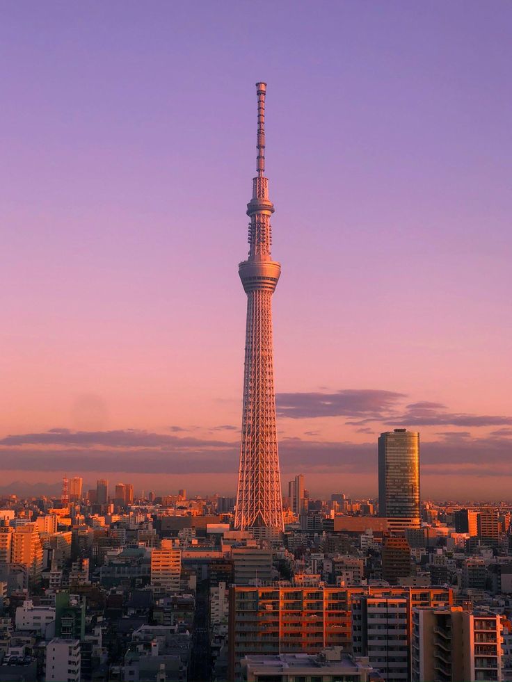 a tall tower towering over a city at sunset