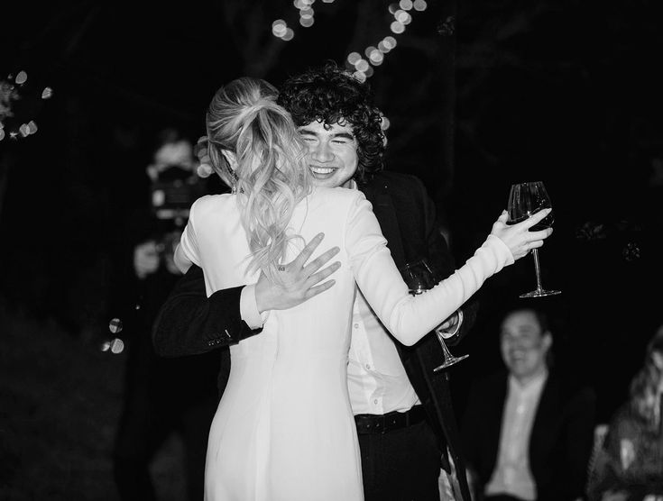 black and white photograph of two people hugging each other at a party with lights in the background