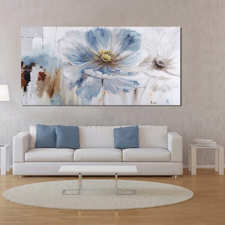 a living room with a white couch and large painting on the wall above it's coffee table