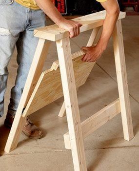 a man standing next to a wooden step stool with his hands on the top and bottom