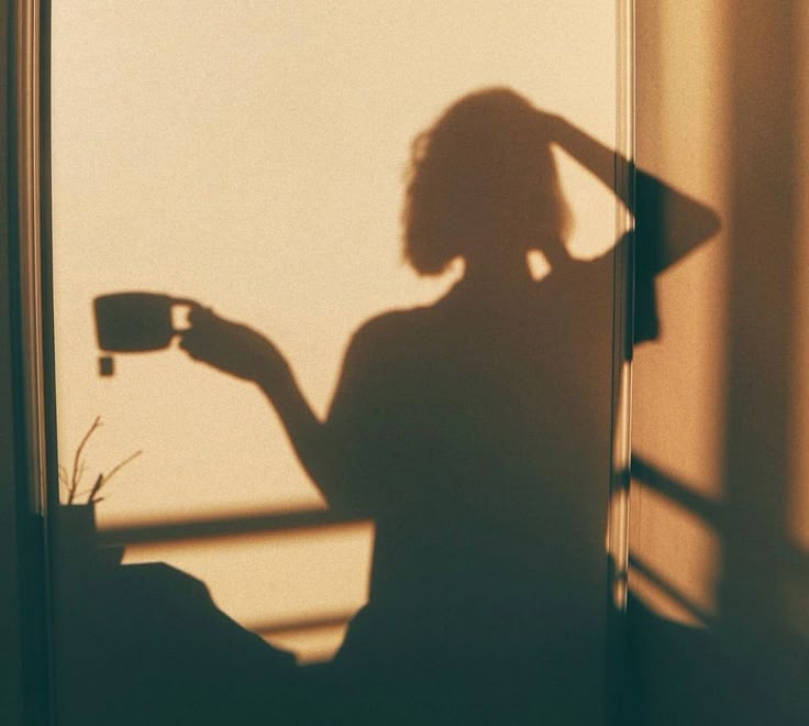 the shadow of a woman holding a cup in her hand