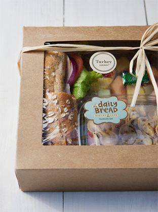 a box filled with different types of bread and other food on top of a wooden table