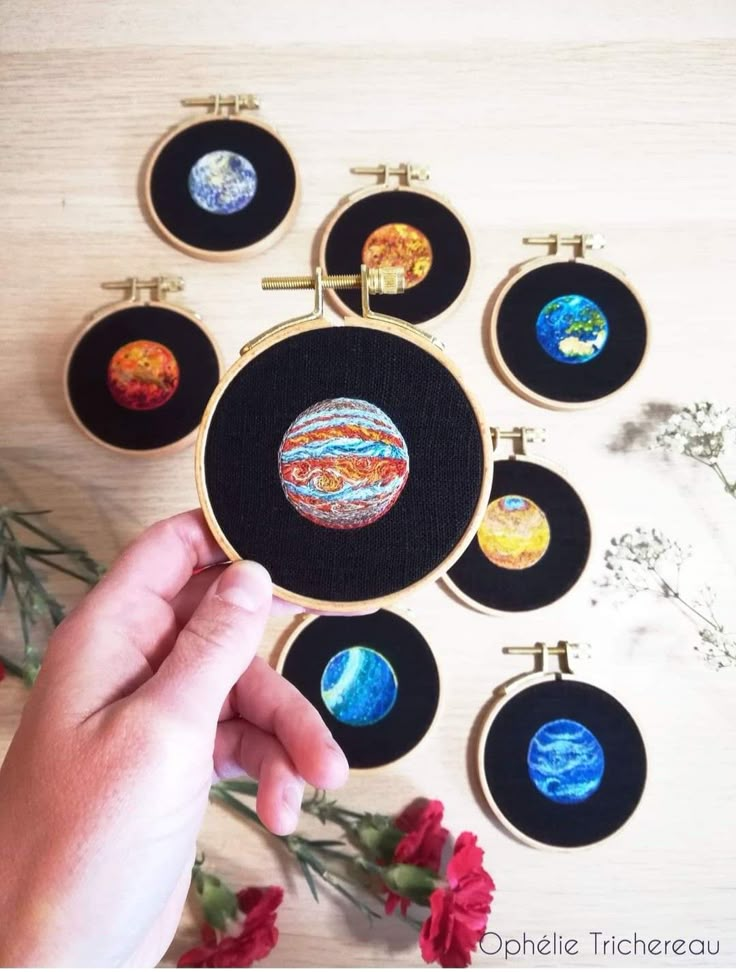 a hand is holding an embroidery project with planets on it