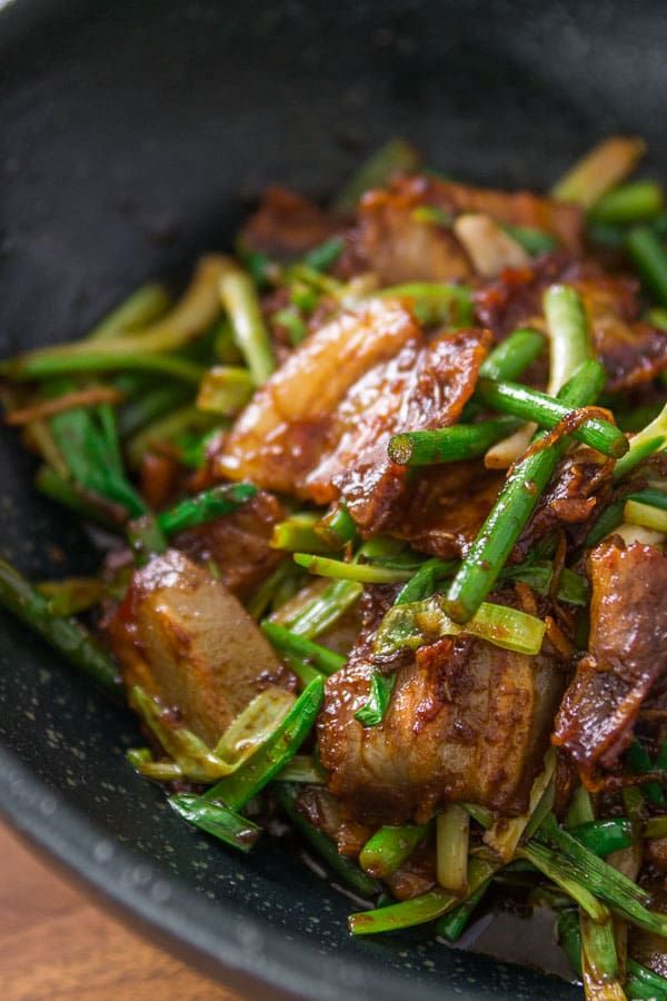 a bowl filled with meat and vegetables on top of a wooden table