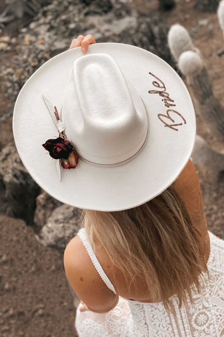 a woman wearing a white hat with the word love written on it in front of cacti