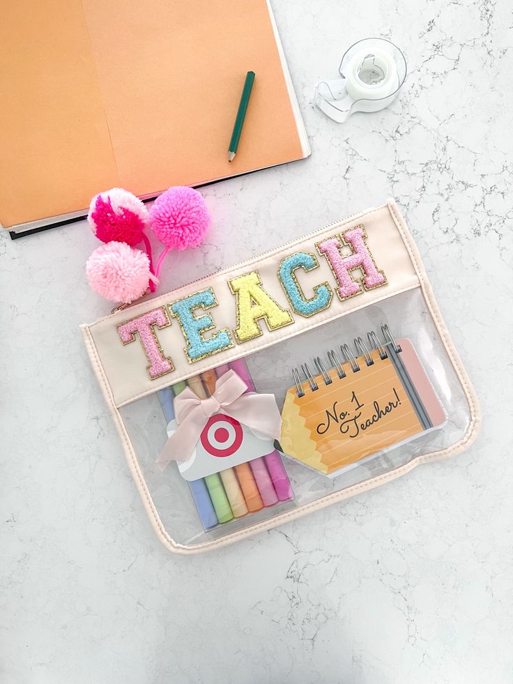 a pencil case with the word teach written on it next to some school supplies and a cup of coffee