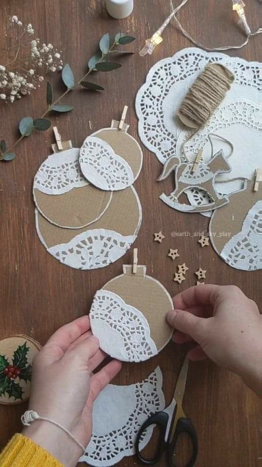 someone making paper doily ornaments on a wooden table