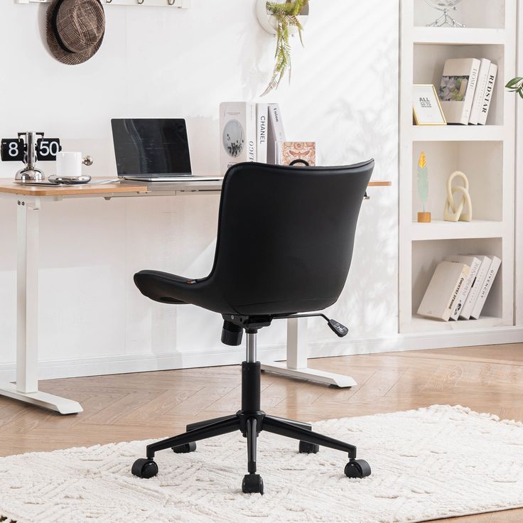 a black office chair sitting on top of a rug in front of a white desk