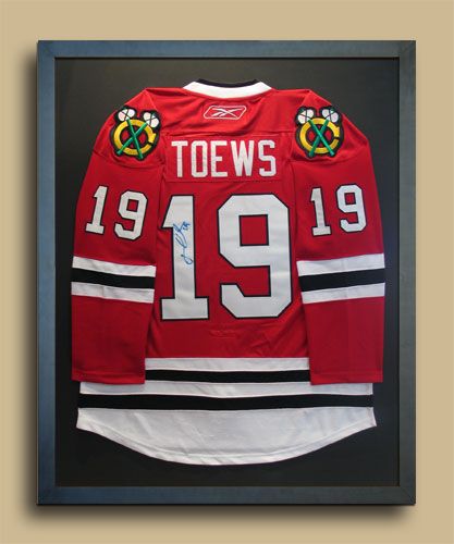 an autographed hockey jersey hangs in a framed frame