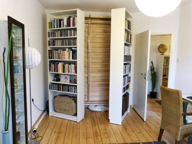 a living room filled with lots of books on top of a hard wood floored floor