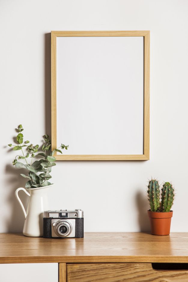 a wooden table with a potted plant and an old camera on it next to a framed photo