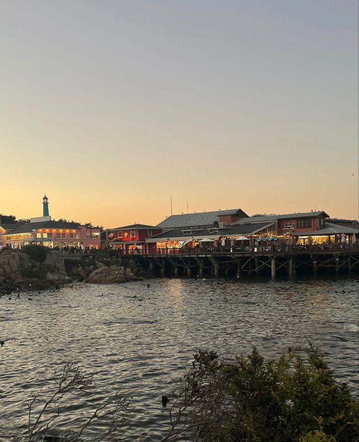 a body of water with buildings on the other side and a lighthouse in the distance