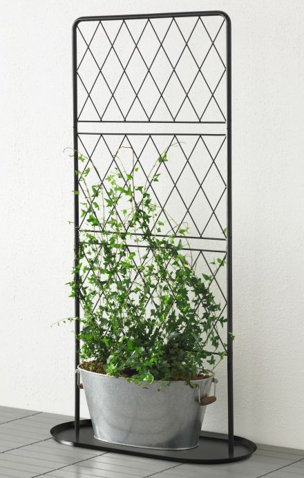 a potted plant sitting on top of a metal stand next to a wall with a white wall behind it