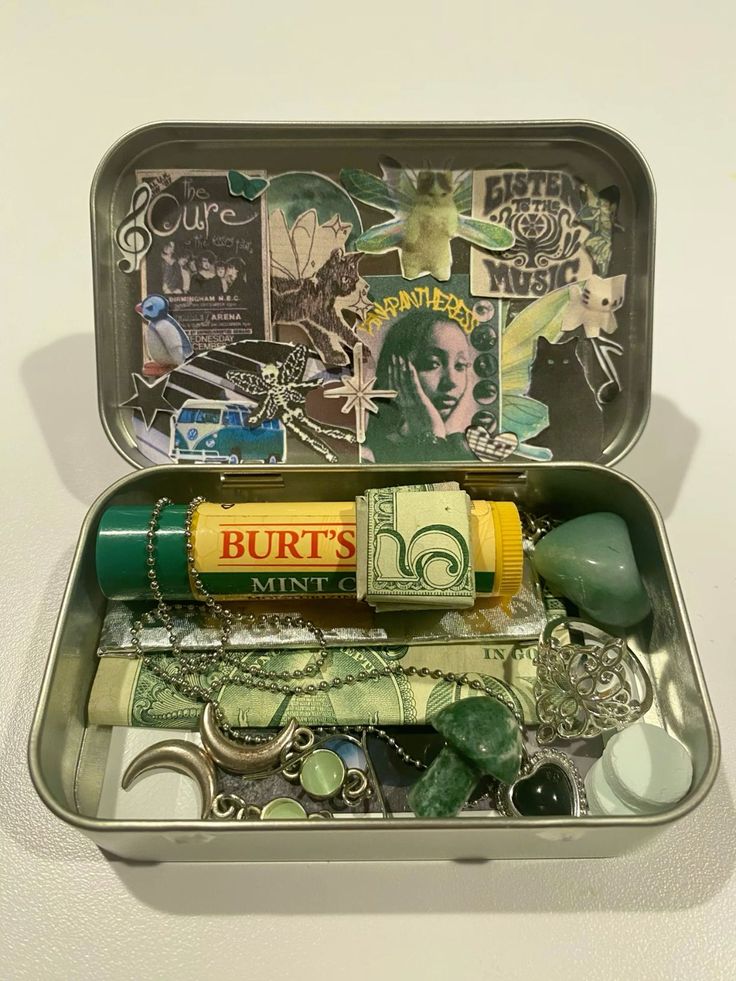 an open tin with various items in it on a white surface, including money and other things