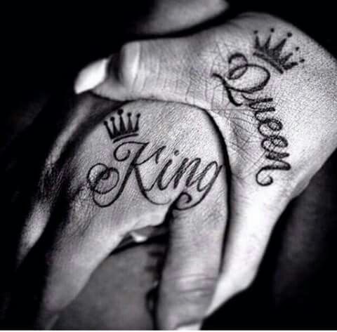 two hands with tattoos that say king and queen