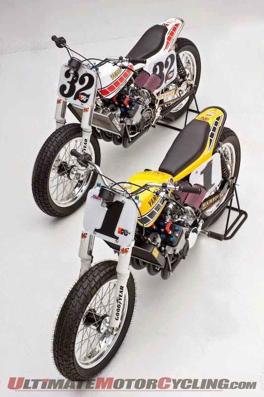 two motorcycles parked side by side on a white surface, one is yellow and the other is black