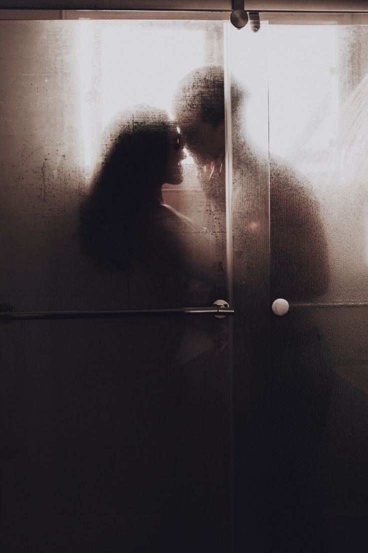 a man and woman kissing in front of a glass door with the sun shining through