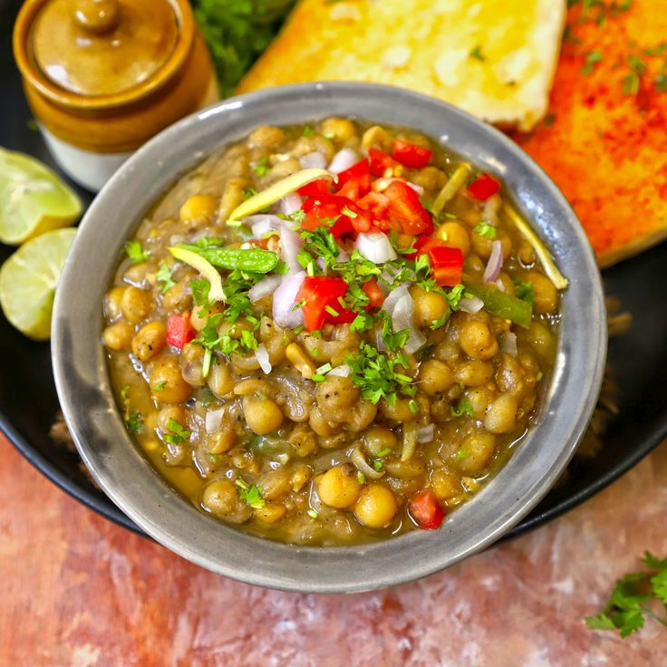 a bowl filled with beans and vegetables next to bread