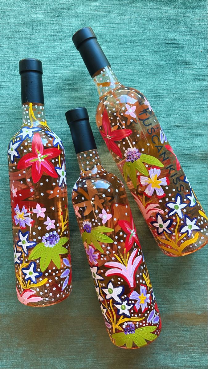 three bottles with designs on them sitting on a table