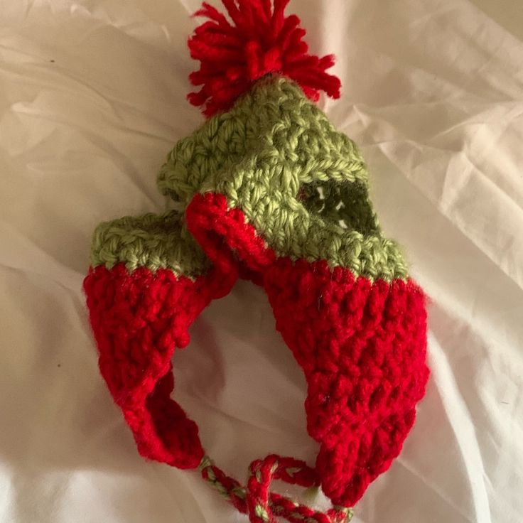 a crocheted green and red hat on top of a white sheet