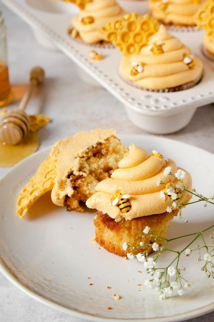 some cupcakes with frosting and honey on them sitting on a white plate