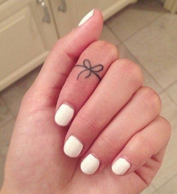 a woman's hand with a small bow tattoo on her thumb and the word love written in black ink