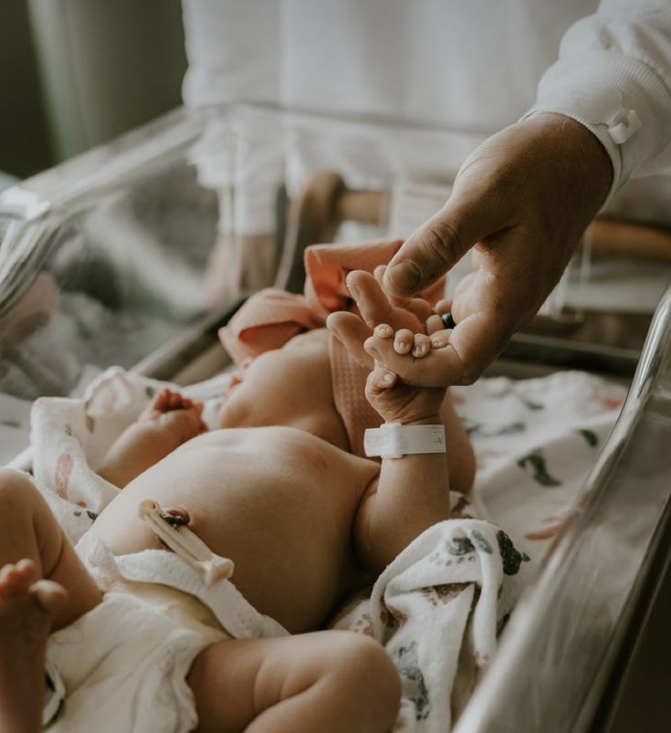 a baby laying on its back in a crib being held by someone's hand