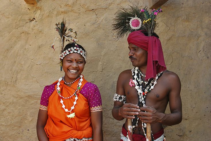 two people standing next to each other wearing headdresses and feathers on their heads