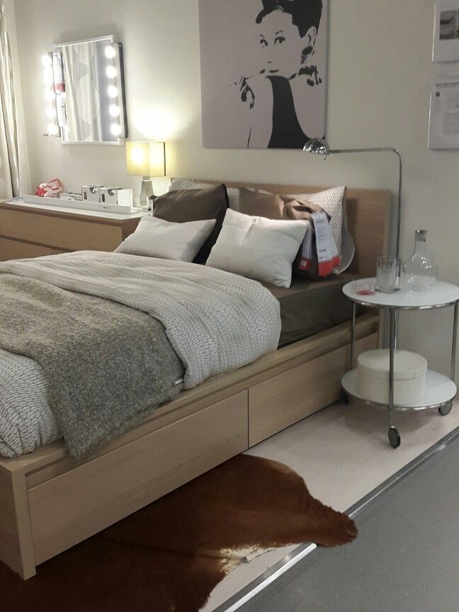 a bed sitting on top of a white floor next to a table with a lamp