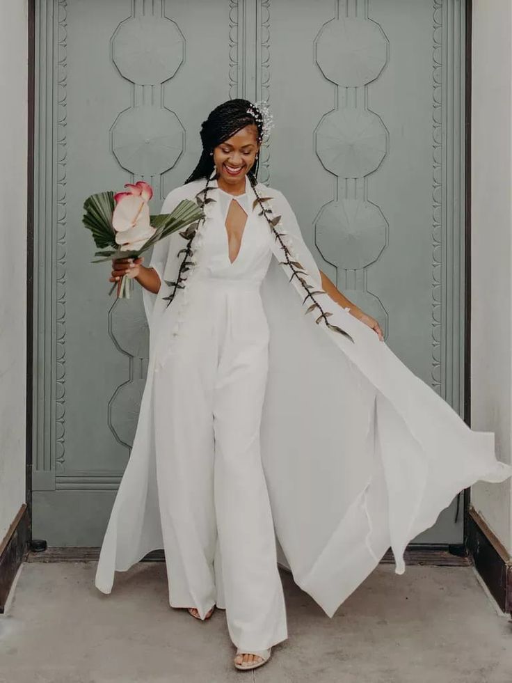 woman in white jumpsuit holding flowers and smiling