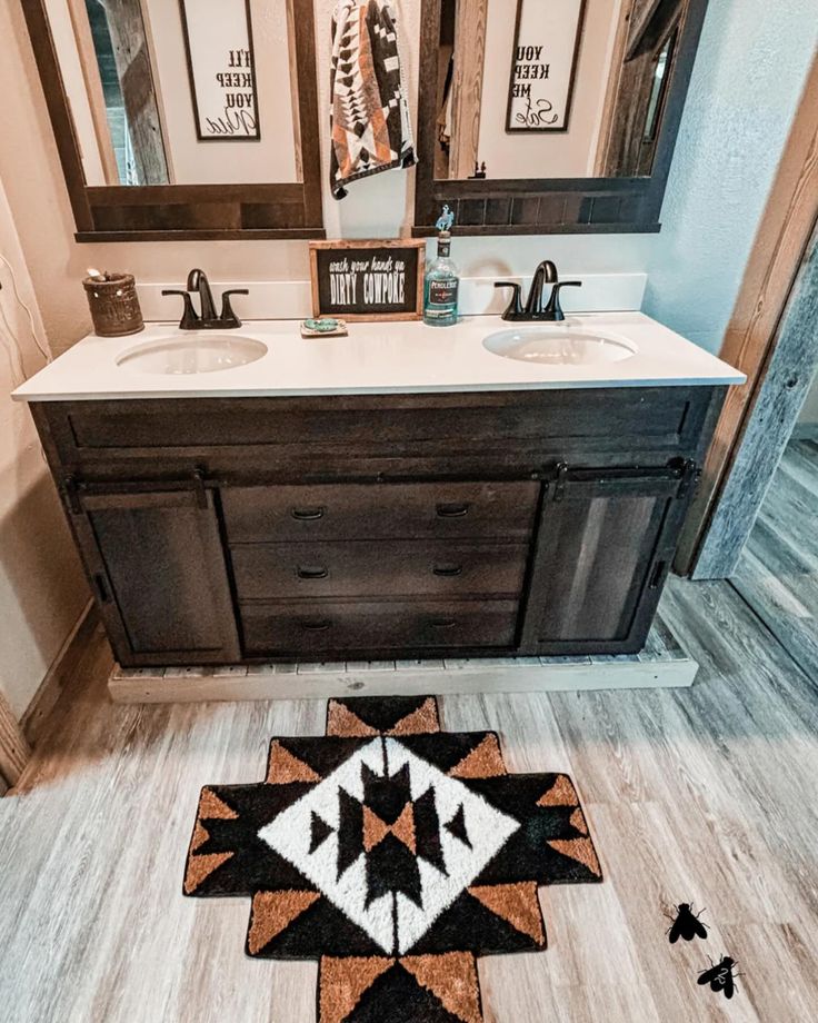 a bathroom with two sinks, mirrors and a rug on the floor in front of it