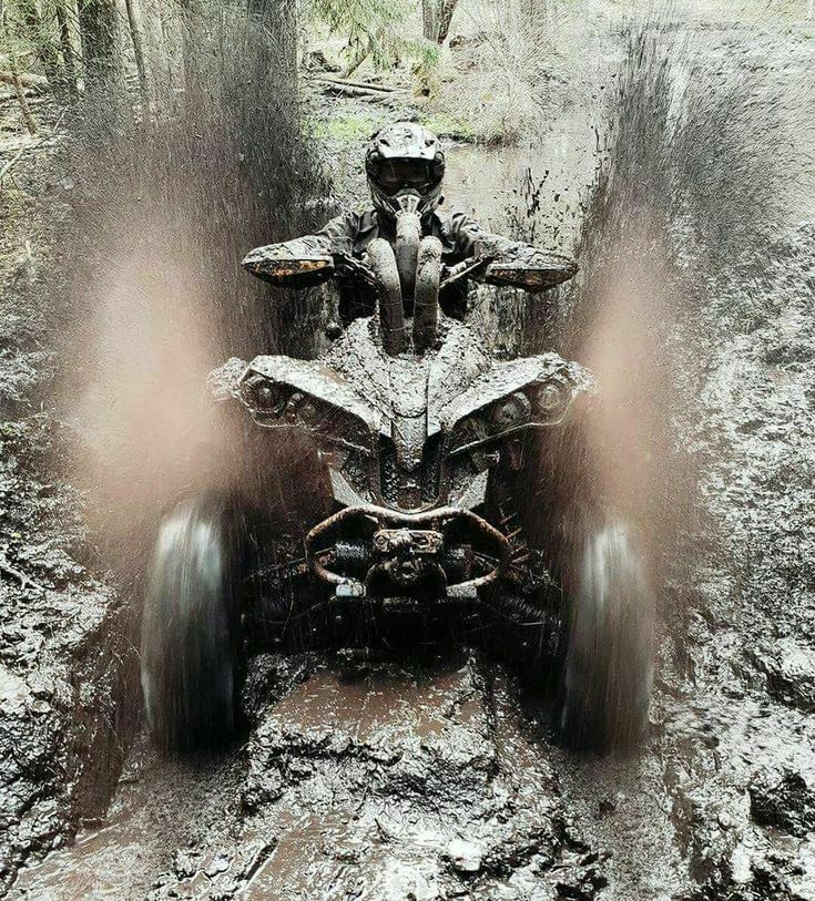 an atv riding through mud in the woods