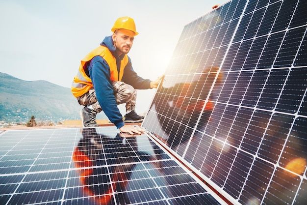 a man working on a solar panel with mountains in the background