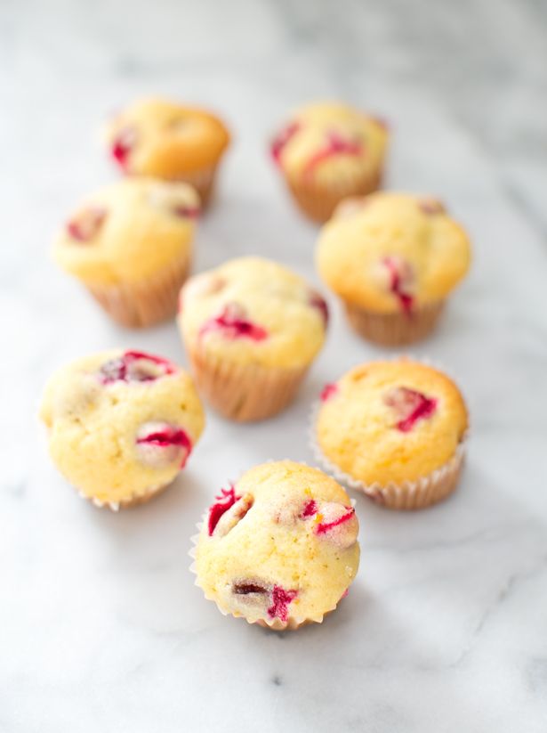 several small muffins with cranberry filling on a white marble countertop