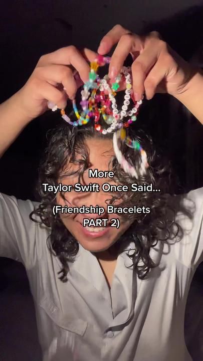 a woman with curly hair is holding her head in front of her face and has beads on it