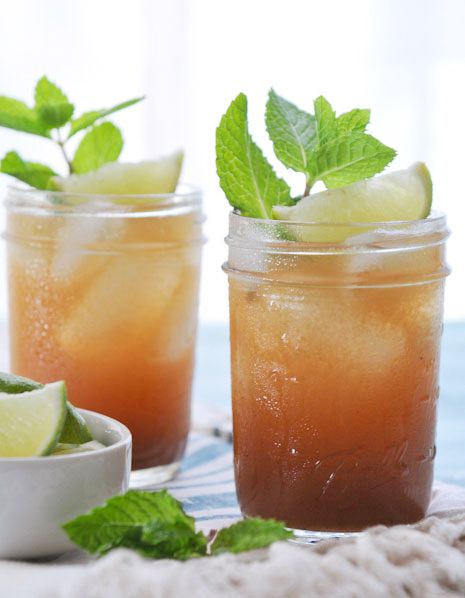 two mason jars filled with lemonade and mint sprits on a tablecloth