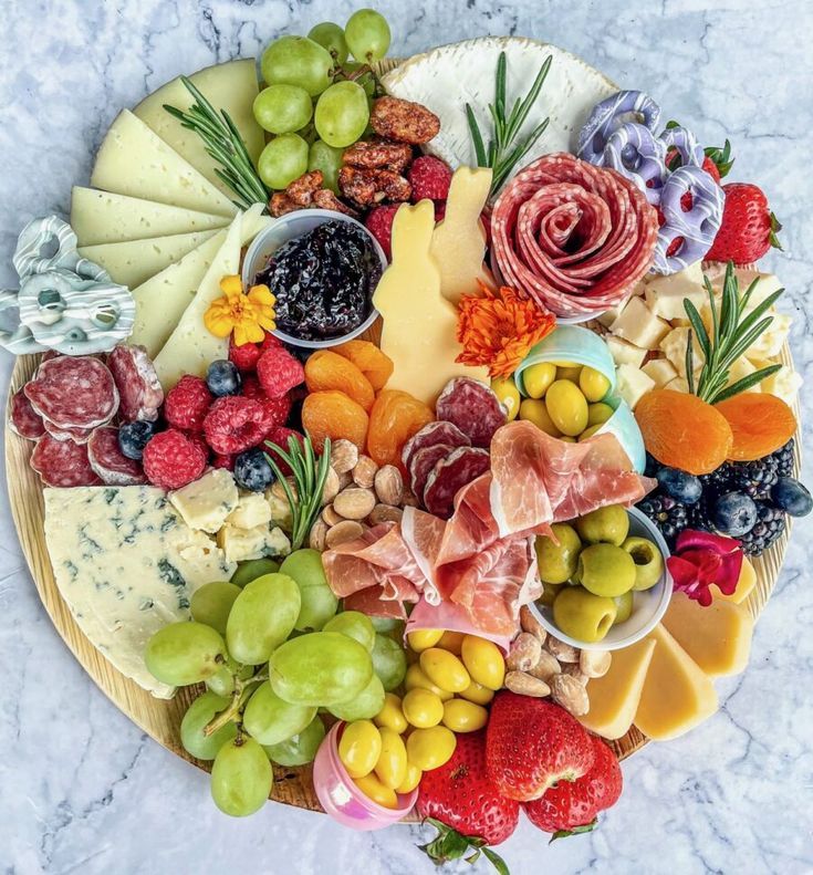 an assortment of cheeses, fruits and meats arranged in a circle on a platter