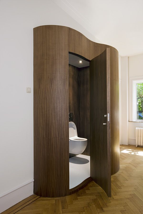 an open bathroom door with a toilet in the corner and wood flooring on the other side