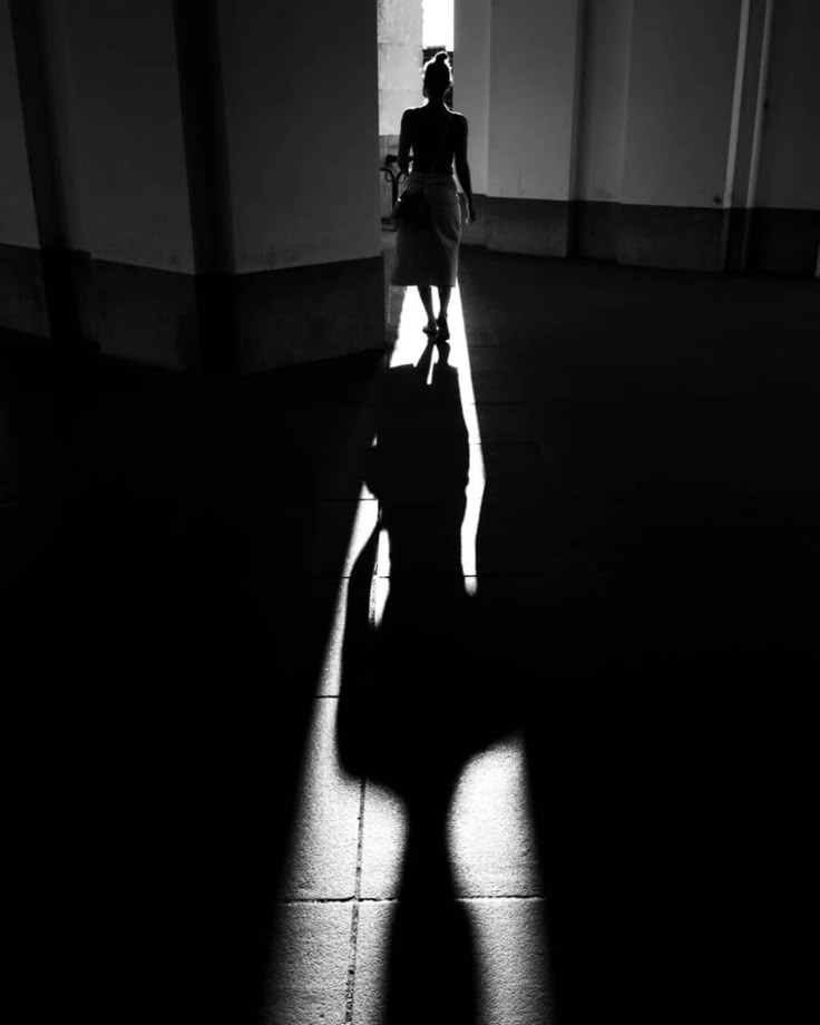 the shadow of a woman walking down a hallway