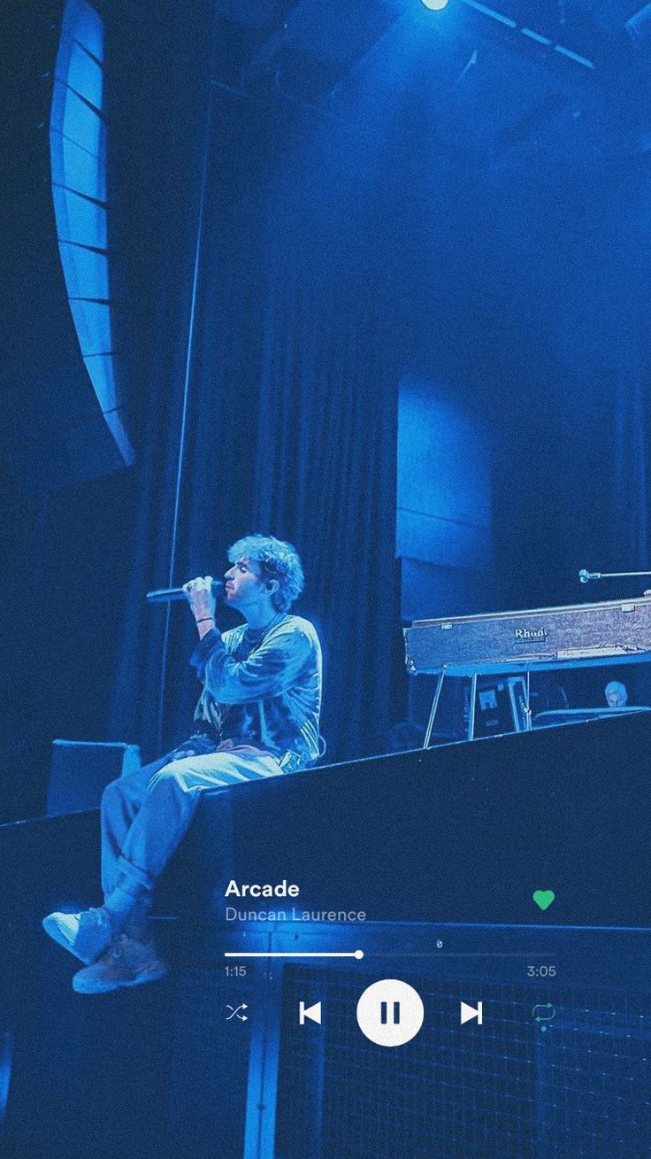 a man sitting on top of a piano in front of a microphone