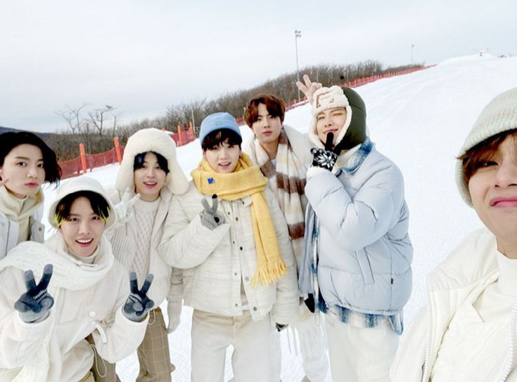 a group of young people standing next to each other on top of snow covered ground