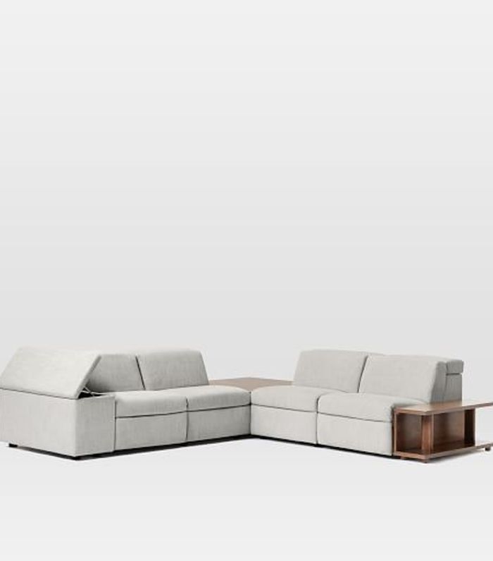 a white sectional couch with wooden legs