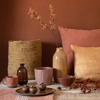 a table topped with vases filled with flowers next to pillows and other decorative items