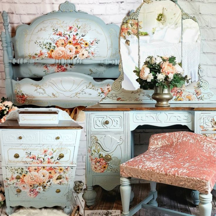 an old dresser with flowers painted on it and a pink chair in front of it