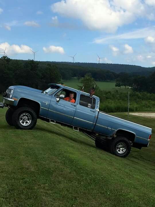 a blue pick up truck parked on top of a lush green field