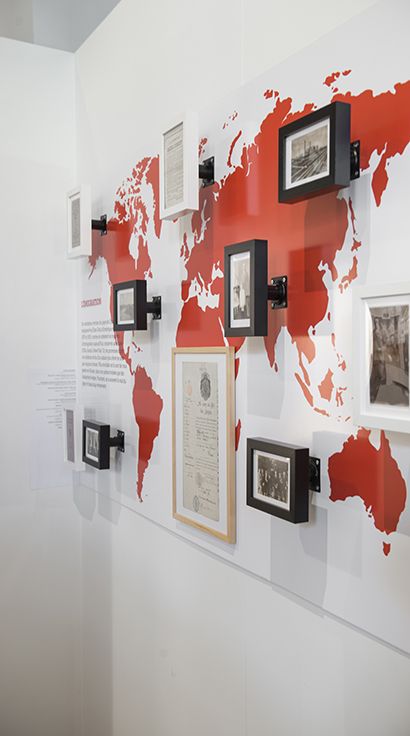 a world map is mounted on the wall with framed photos and pictures hanging from it's sides