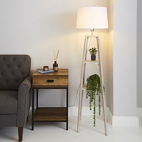 a living room with a chair, table and lamp next to the wall in front of it